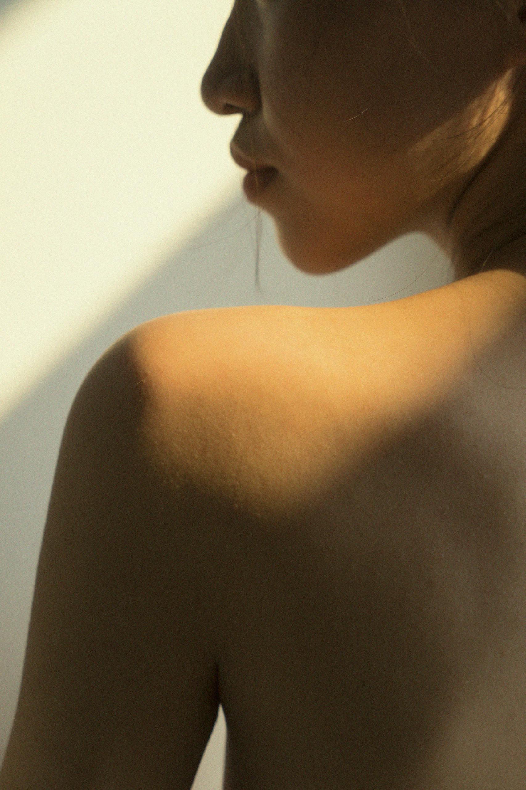 Artistic close-up of a woman's bare shoulder in soft lighting.